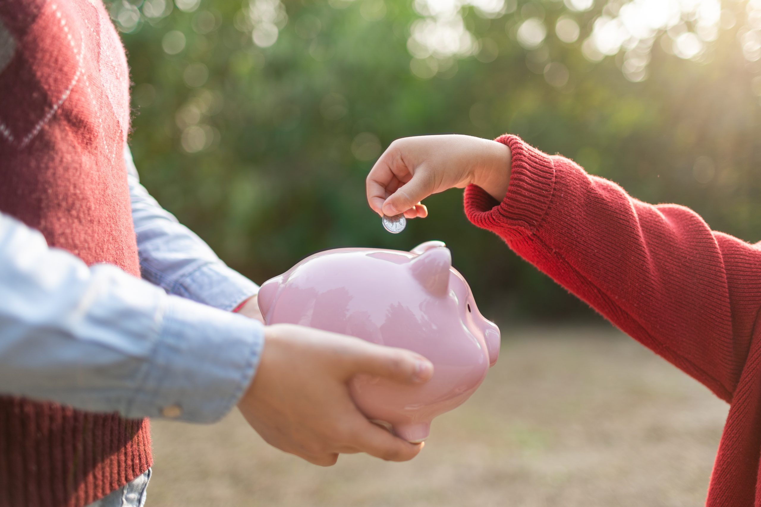 Kind wirft Geld in Sparbückse
